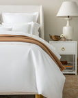 close up of the Lisetta Duvet cover in champagne with the Savona throw in camel