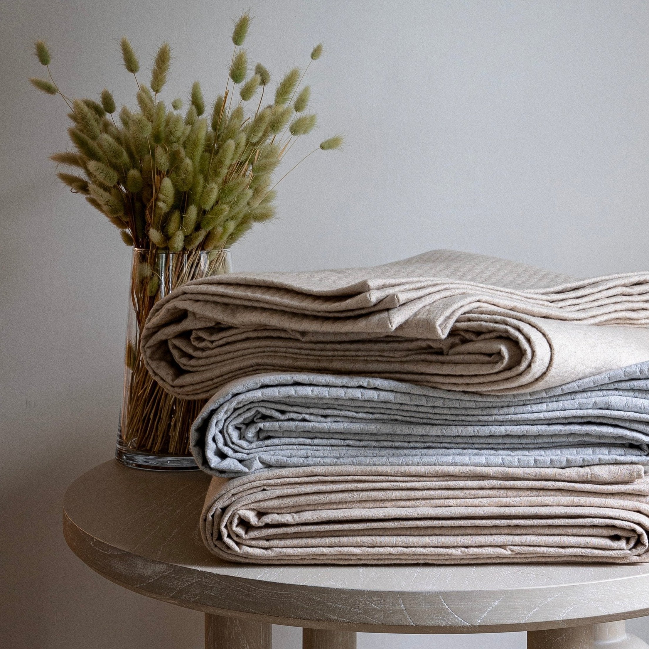Stacked image of Ravello Coverlets in all three colors: linen, cove and pearl