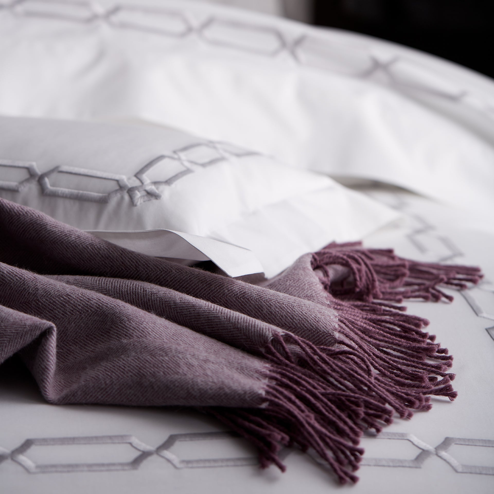 close up detail of arezzo chain embroidery in the color shadow &amp; white on bed with purple alpaca throw, 