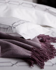 close up detail of arezzo chain embroidery in the color shadow & white on bed with purple alpaca throw, 
