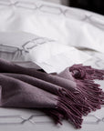 close up detail of arezzo chain embroidery in the color shadow & white on bed with purple alpaca throw,