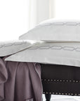 arezzo embroidered standard shams in the color shadow & white on bench with cashmere blanket,