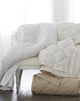 scandia home down blankets in white, ivory and café folded and draped over a sette 
