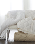 scandia home down blankets in white, ivory and café folded and draped over a sette