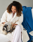 woman wearing the down robe in ivory with her dog on a chair