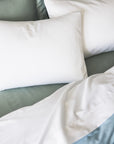 close up detail shot of the stresa sateen flat sheet in white with white pillowcases