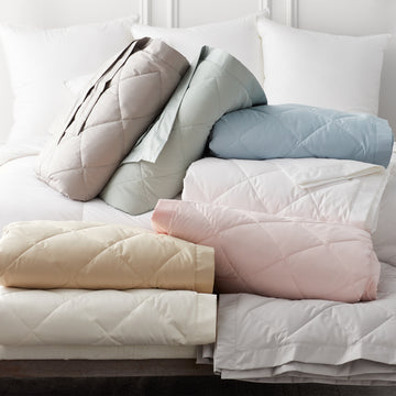 scandia home down blankets in every color selection folded on a bed