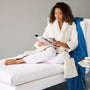 woman wearing the down robe reading on a sette 