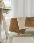 indulgence bath rugs in the colors bronze and ivory draped over bath tub