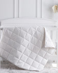 scandia home crib comforter in our classic white shell filled with european white down drapped over a crib